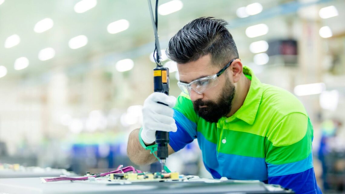a man in a factory working on a piece of equipment